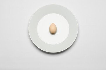 egg in the shell lies on a white plate on a white background