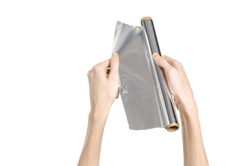human hand holding a roll of foil on a white background