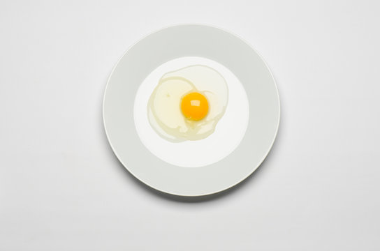 raw egg lays on a white plate on a white isolated background