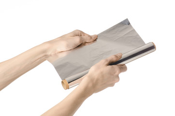 human hand holding a roll of foil on a white background