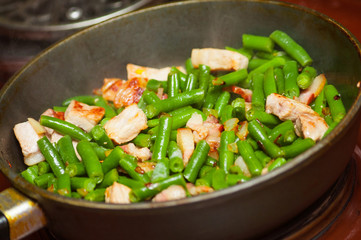 Cooking meat with green beans in fried pan