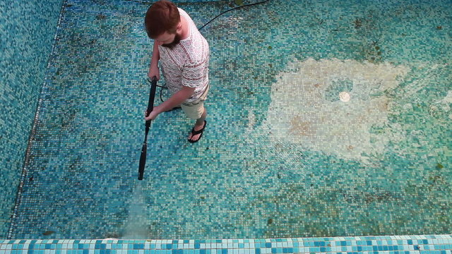 A man is cleaning the pool wall 
