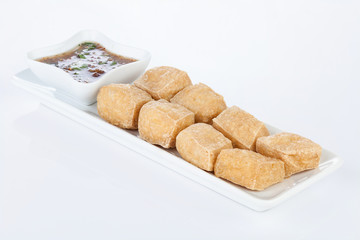 Deep Fried Tofu on white dish with Sweet & Sour Sauce.