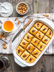 homemade baklava with honey and walnuts in a white bowl on a woo
