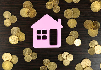 Model of house with coins on wooden table, closeup