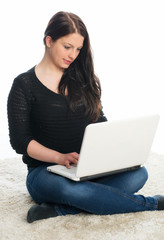 Frau sitzt auf dem Boden und chattet am Laptop