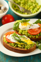 Fototapeta na wymiar Tasty sandwiches with egg, avocado and vegetables on plate, on wooden background