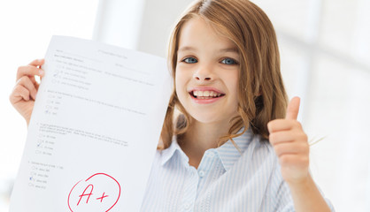 smiling little student girl with test and A grade