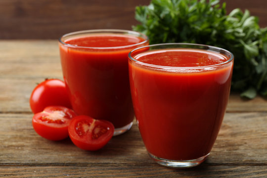 Glasses of fresh tomato juice on wooden background