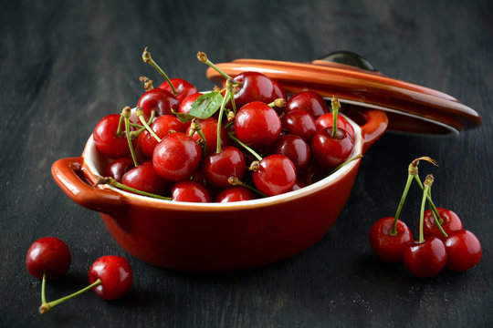 Ripe cherries in red pan on dark background