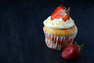 Capcakes with strawberries on dark background