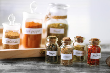 Assortment of spices in glass bottles on wooden background