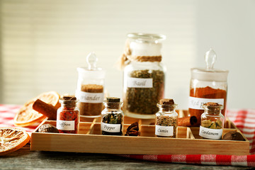 Assortment of spices in glass bottles in box, on light background
