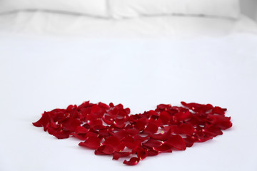 Heart of red petals on bed, close up