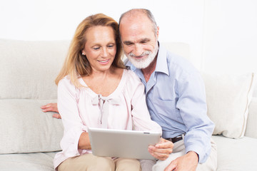 Happy elderly couple looking at a tablet