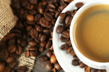 Cup of coffee with beans on table close up