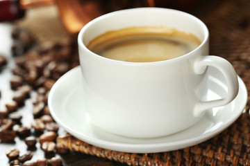 Cup of coffee with beans on table close up