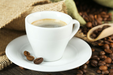 Cup of coffee with beans on table close up