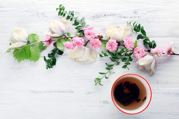 Cup of tea with beautiful flowers on wooden background