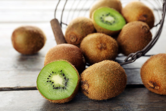 Ripe kiwi in basket on wooden table close-up