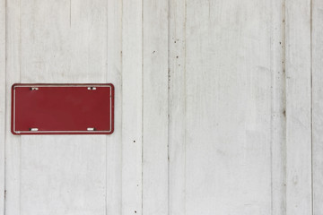 Empty metal sign on a white wooden wall.