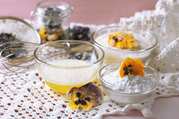 Making candied violet flowers with egg whites and sugar, on color wooden background