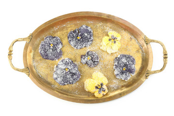 Candied sugared violet flowers on tray, isolated on white