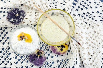 Making candied violet flowers with egg whites and sugar, on color wooden background