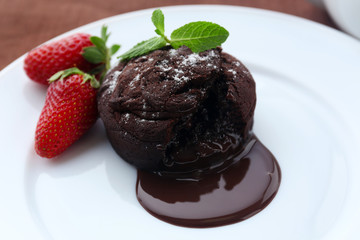 Chocolate fondant with strawberries on white plate, closeup