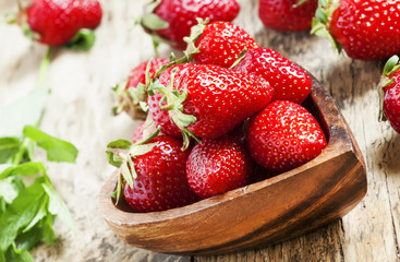 Fresh organic strawberries in a bowl in the shape of a heart, se