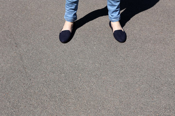 Fototapeta na wymiar Female feet on gray asphalt background