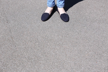 Female feet on gray asphalt background