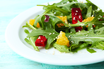 Tasty salad with arugula leaves in plate on wooden table, closeup