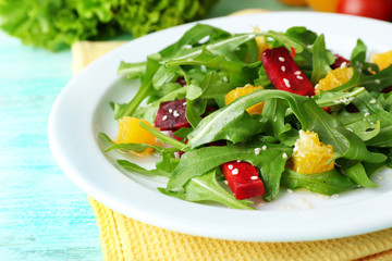 Tasty salad with arugula leaves in plate on wooden table, closeup