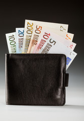 Euro banknotes in leather wallet on dark background