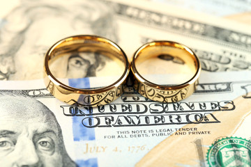 Golden wedding rings on banknotes background. Marriage of convenience