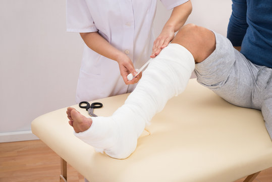 Doctor Bandaging Patient's Leg