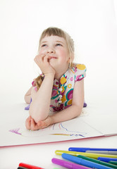 Smiling little girl lying on the floor and thinking