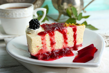 Tasty piece of cheesecake with berry sauce on plate on table close up