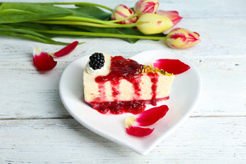 Tasty piece of cheesecake with berry sauce on plate on table close up