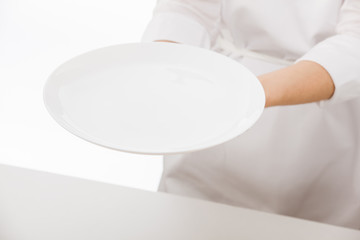Woman's hands holding an empty plate on white background