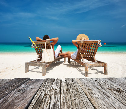 Couple in white relax on a beach at Maldives