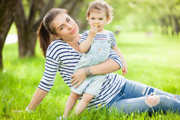 Fototapeta premium Portrait of a beautiful young woman with a small child in park