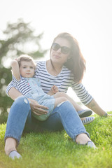 Fototapeta premium Portrait of a beautiful young woman with a small child in park