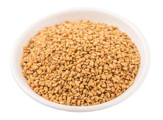 Fenugreek seeds in white bowl over white background