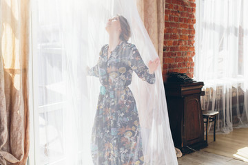 girl opening curtains in a bedroom