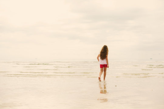 Young teen girl walking on sea shore