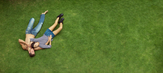 beautiful love couple lying in a meadow. Grass nature background, space for text