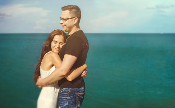 Happy couple in love hugging outdoor near blue sea