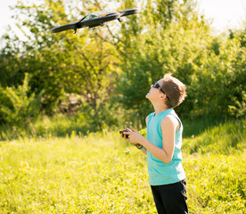 Boy with flying drone with camera controlled by smartphone. 